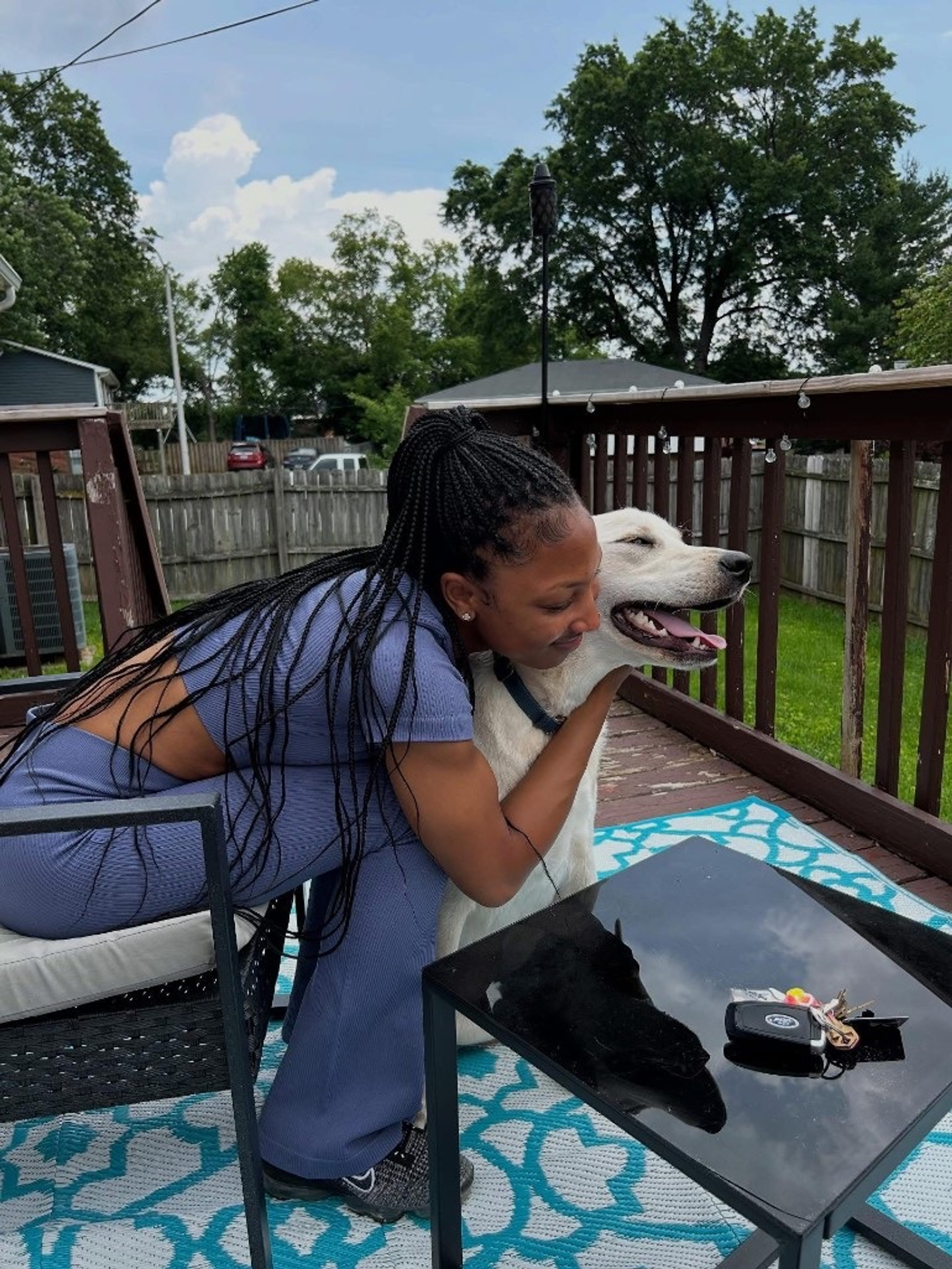 Shai Walker hugging a happy white dog on the deck